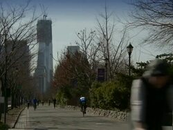 Biker and runners exercise on a bike path on the Hudson River Park on the West Side of Manhattan, the freedom tower is behind under construction Stock Footage