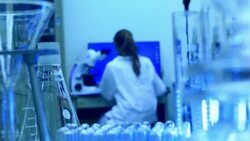 Laboratory glassware with technician in background Stock Footage