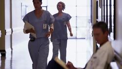 Nurses walking past doctor in hospital corridor Stock Footage