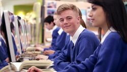 Boy looking at camera while studying in school computer lab Stock Footage