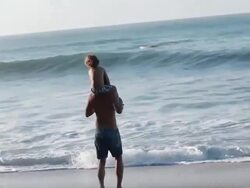 MS TS Man runs into wavebreak with boy on shoulders / Montezuma, Puntarenas, Costa Rica Stock Footage