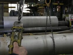 Camera follows crane hook as Caucasian worker presses controls to raise payload in factory Stock Footage