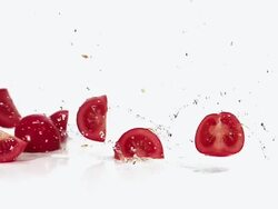 MS SLO MO Tomato quarters falling and sliding on water against white background / Vieux Pont, Normandy, France  Stock Footage