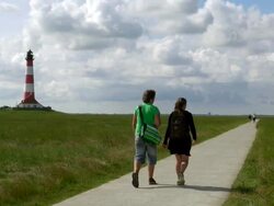 WS View of couple walking through walking trails near Westerhever lighthouse and clouds moving over / Westerhever, Schleswig Holstein, Germany Stock Footage