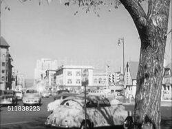 1950: DENVER, COLORADO: STREET SCENES: Cars moving on road & turning off at intersection. DOWNTOWN: People crossing street at urban intersection. (POV Center street) Cars driving on two-lane road w/ other automobiles parked curbside. Instructional Video