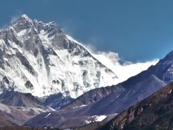Time-lapse of the tip of Everest and surrounding peaks and trekkers on a foreground trail. . Cropped. Stock Footage