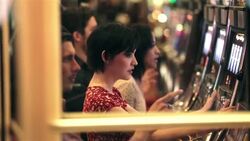 Hopeful young woman cranks slot machine and hits jackpot, jumps up and celebrates with friends Stock Footage