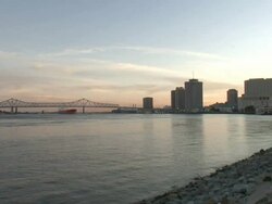 Wide Shot - Bridge, river, boat, and buildings along coastline at sunset / New Orleans Louisiana Stock Footage
