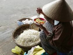 WS Woman eating bowl of noodles at her roadside stall selling eggs and beansprouts Stock Footage