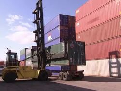 A crane carries a shipping container towards a truck. Stock Footage