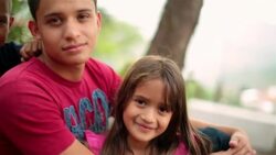 Hispanic teenage brother and younger siblings stare into camera Stock Footage