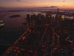 Aerial -Evening shot over lower east side of Manhattan pivoting around the financial district and the Freedom Tower. The Manhattan and Brooklyn bridges pass in the foreground. Stock Footage