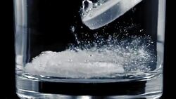 SLO MO Two fizzing tablets dissolving on bottom of glass Stock Footage