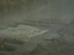High Speed Rain falling on UK five pound note and coins in drain Stock Footage