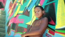 Brazilian boy crosses arms and stares at camera on graffitied wall in Rio Stock Footage