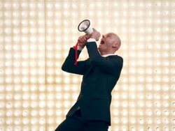 Man with megaphone in front of lightwall Stock Footage