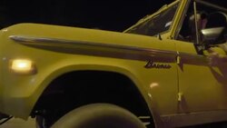 Young man driving classic Ford Bronco with friends drums on door and speeds up Stock Footage