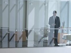  PAN Businessman looking at cell phone before walking away, seen through interior windows / Seattle, Washington, United States Stock Footage