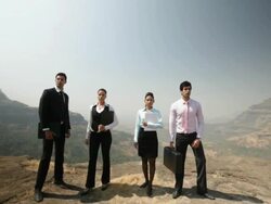 Four business people standing on the cliff of mountain Stock Footage