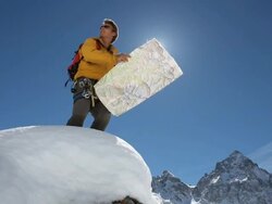 Mountaineer reads map on snowy ridge crest, looks off Stock Footage