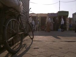Street shot with pedestrians moving past stalls, bicycle parked in foreground, El Bizri, Egypt (sound available) Stock Footage
