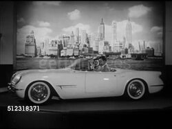 1953: AUTOMOBILE DESIGN: WS Male & female in Chevrolet corvette convertible rotating on stage w/ New York City backdrop. WS Lincoln XL500 Concept car on stage. Two women dressed in cocktail dresses getting into GM Buick Le Sabre futuristic concept car. Instructional Video