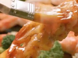 ECU brush basting barbecue sauce over shrimp stacked tight on skewer over grill with king crab legs in background Stock Footage