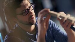 Young craftsman chisels flexible wooden chair frame in furniture workshop Stock Footage