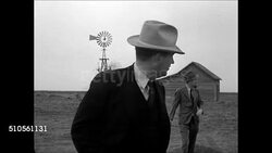 1937: 1933 REENACTMENT: HD: Publisher John L. McCarty looking around at abandoned farm w/ his reporter. WS Abandoned farm house. WS Abandoned farm (dark contrast). MS John L. McCarty standing beside automobile talking w/ his reporter.  Great Depression. Instructional Video