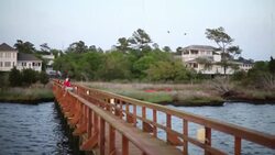Young boys on dock gather fishing rope as pelicans fly overhead Stock Footage