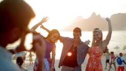 Friends pose at sunset for smartphone photos on the beach at Ipanema Stock Footage