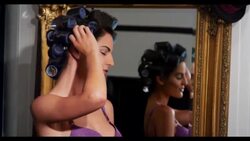 A woman by a mirror with her hair in rollers Stock Footage