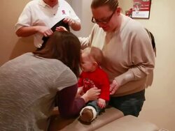 MS Mother places baby on chiropractic bed for female chiropractor to examine with dad / Toronto, Ontario, Canada Stock Footage