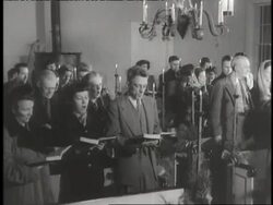 Worshipers hold hymnals as they stand and sing during a church service. News Clip