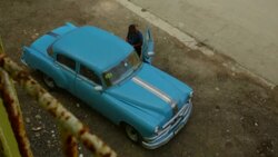 man standing by his vintage car with rusted fence in shot Stock Footage