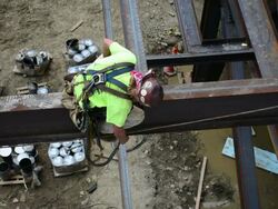 Steelworker with a hard hat connects his harness at a construction site Stock Footage