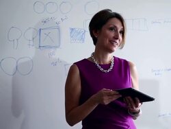 CU Mature businesswoman holding digital tablet in discussion with coworkers laughing standing at whiteboard/Washington, USA Stock Footage