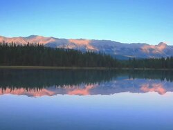 Mountains at sunset reflecting their glow in Alpine Lake Stock Footage
