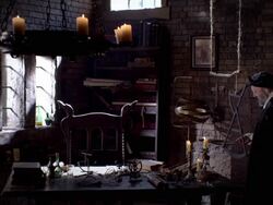 A man in period clothing picks up a pen below a chandelier of flickering candles. Stock Footage