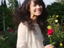 CU SLO MO TS Shot of beautiful brunette playfully smiles, picks rose and flirts in sunny garden / Portland, Oregon, United States  Stock Footage