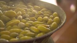 A fork stirs silk cocoons that boil in a kettle while the silk threads are gently pulled away. Stock Footage