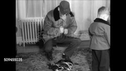 1950: AMERICAN FAMILY: EXT Middle Class home. INT Home w/ father, mother, two boys putting on warm clothing, jackets, hats, father's hands picking up ice skates, leaving house, family getting into car, driving away. (AAA sticker on trunk). Instructional Video