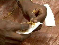 Ethiopian man rolls cigarette at market Stock Footage