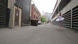 Young ballerina leaping in urban alley Stock Footage