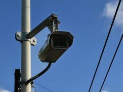 "MS LA ZI T/L Shot of Circuit Television Camera surveillance people reflecting in lens power cables through frame white clouds in blue sky in back side / London, Greater London, United Kingdom" Stock Footage