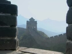 Close-up of a tower that lies along the Great Wall of China, then panning out to view the mountains in the background with the wall running along the tops.  Stock Footage