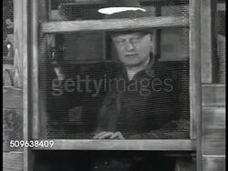 1941: 'THE STUART CASE': Collection of new Gas Masks hanging on wall. Elder male locking up stock room containing gas masks, talking to 'Mr. Stuart' about locking up, never lost anything. CU Elder male hands locking pad lock on wooden door. Instructional Video