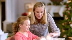 Proud mother helps daughter press Christmas cookie-cutter shapes into cookie-dough (dolly-shot) Stock Footage