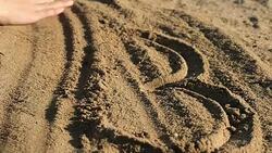 Female hand erasing heart shape in sand Stock Footage