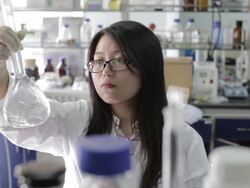 Asian female scientist looking at beaker of liquid Stock Footage